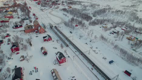 Atemberaubende-Luftaufnahme-über-Roten-Häusern-Im-Winter-In-Abisko,-Schweden