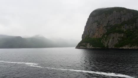 View-of-mountains-from-the-stern-of-a-ship-cruising-along-Saguenay-Fjord-outside-of-La-Baie,-QC,-Canada