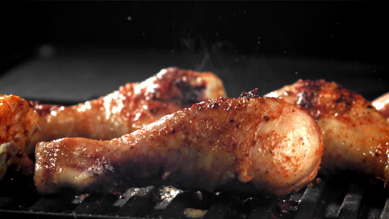 Fusi di pollo che grigliano su un barbecue caldo al rallentatore