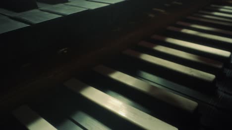 grand piano keyboard, camera moves forewards to the right, slow motion, closeup, dark, black