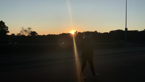 silueta de mujer rubia joven y bonita caminando por la calle frente al sol poniéndose