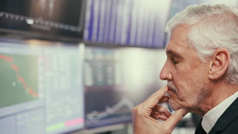 un hombre de negocios se sienta frente a las pantallas de las computadoras y parece preocupado.