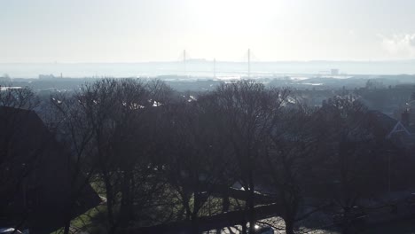 Frosty-mist-surrounding-urban-British-town-house-rooftops-aerial-view-early-morning-panning-left-across-park-trees