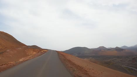 Timanfaya,-Imágenes-Desde-La-Carretera,-Parque-Natural-Volcánico-De-Lanzarote-Conduciendo-Por-La-Carretera-Desde-El-Punto-De-Vista-Frontal-Del-Coche-Paisaje-Lunar