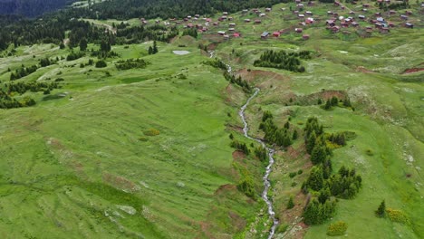 flying over green hills, river and woodland in highland countryside of georgia