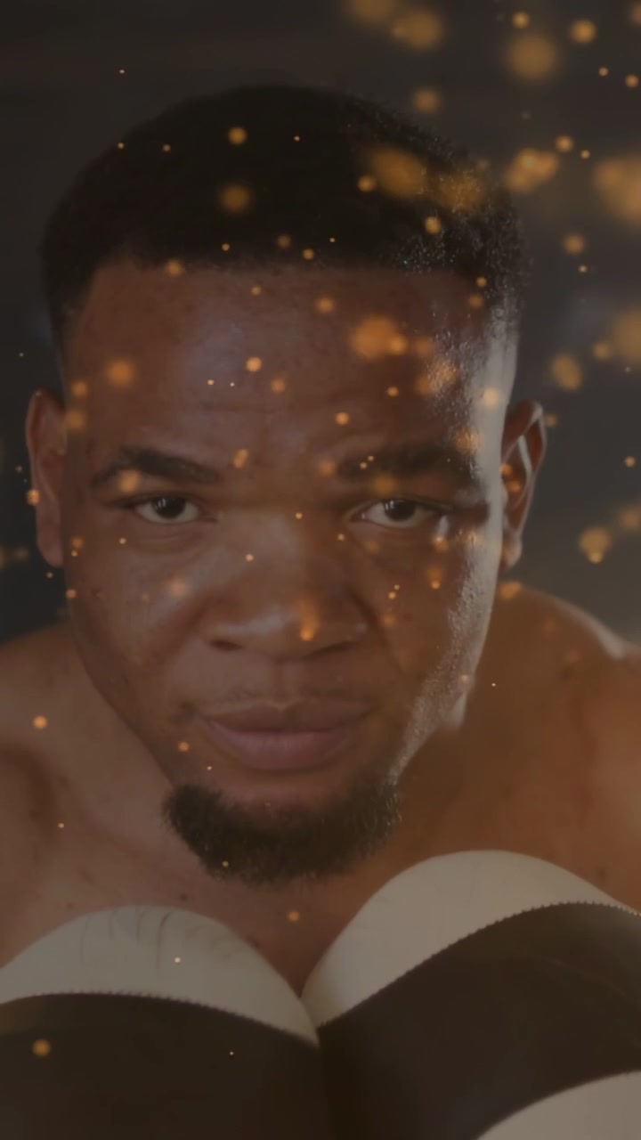 Vertical video: Boxer thrusting glove at lens, punching jabs for fitness, bokeh floating over glove