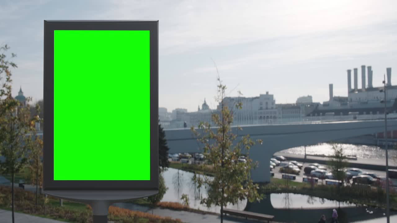 Empty billboard with a green screen for advertising in the Park on the beautiful river embankment, autumn sunny shot