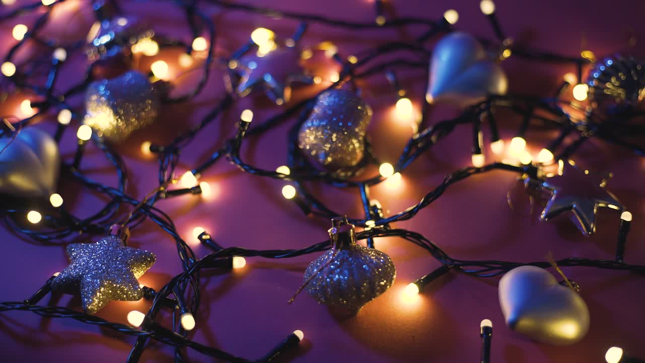 Close-up shot of garland with golden lights and christmas toys on color background. Christmas concept. Home decor. Beautiful bokeh
