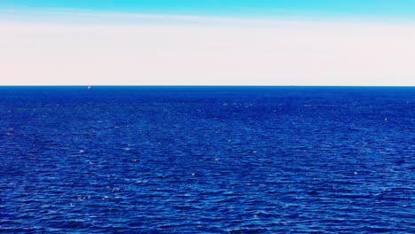 baltic sea expansive, low-angle view capturing the deep, serene blue waters under a clear, bright sky transitioning from white to light blue at the horizon subtle surface ripples distant visible boat