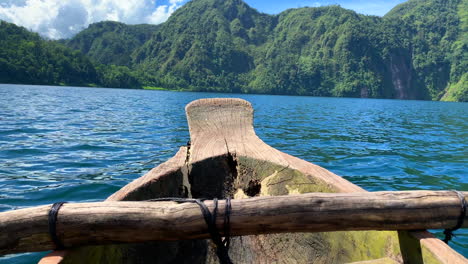 An-8-seconds-footage-of-a-single-wooden-boat-roaring-into-the-lake-with-green-forest-in-the-background