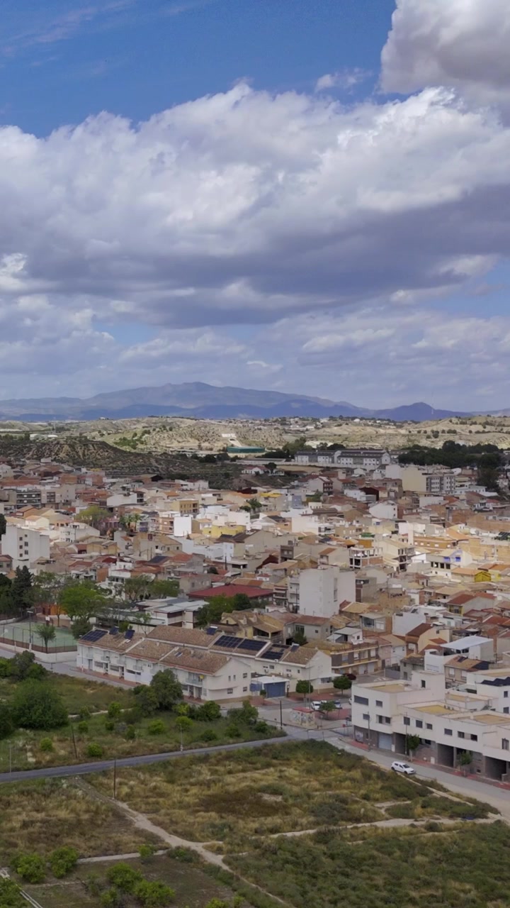 Vista verticale da drone di una cittadina mediterranea circondata da frutteti, terreni agricoli, vegetazione e montagne distanti a Murcia