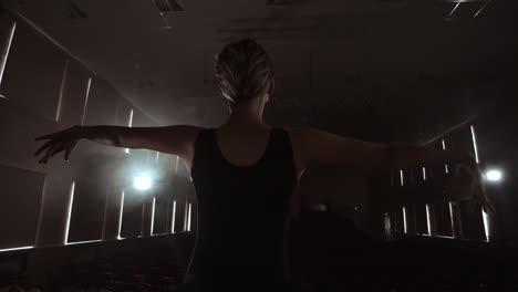 slow motion: prima ballet on stage rehearsing performance in the dark light of the contra. the lights from the hall