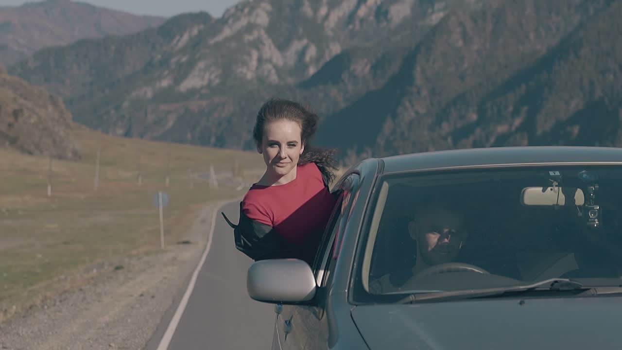 mujer tranquila se sienta en la ventana del coche acelerando y mira a la cámara
