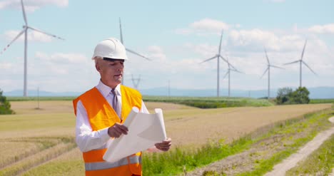 engineer reading plan against wind turbine farm 2