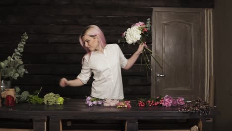 fashionable, smiling girl florist in the process of decoration a bouquet of flowers. slow motion. indoors