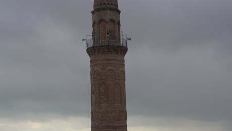 Al-Inclinar-La-Cámara-Hacia-Arriba,-Comenzando-Desde-La-Cúpula-De-La-Mezquita-Mardin-Ulu-Y-Escaneando-El-Minarete,-Se-Ve-El-Balcón-Del-Minarete