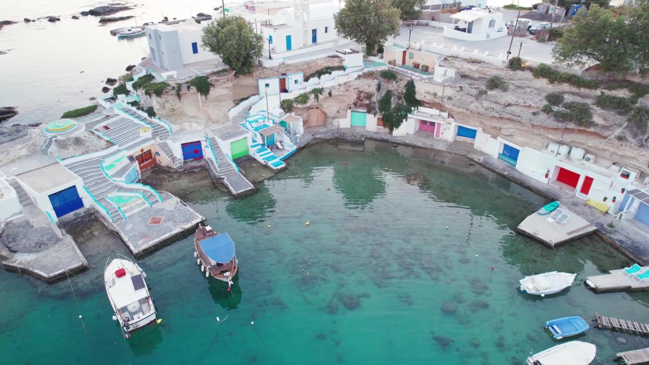 Syrmata colorate e scalinate dipinte costeggiano una baia tranquilla in questa vista aerea di Mandrakia, un tradizionale villaggio di pescatori a Milos, Grecia