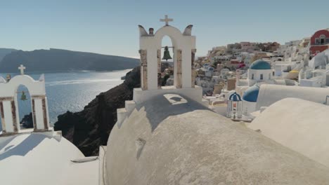 panorámica sobre coloridas flores y campanas de la iglesia griega con fondo de vistas al mar en santorini, grecia