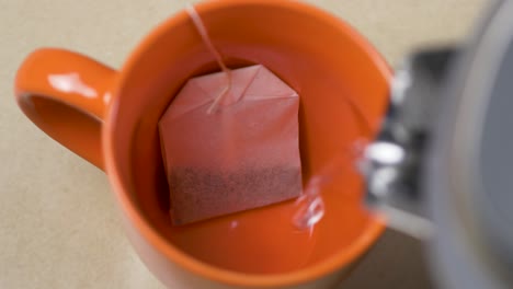 close-up slow motion shot of pouring hot boiled jug kettle water into tea cup mug with tea bag beverage kitchen breakfast aroma morning 4k