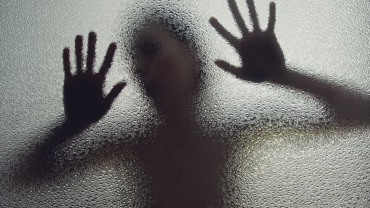 A female silhouette behind the frosted window touches the glass slowly