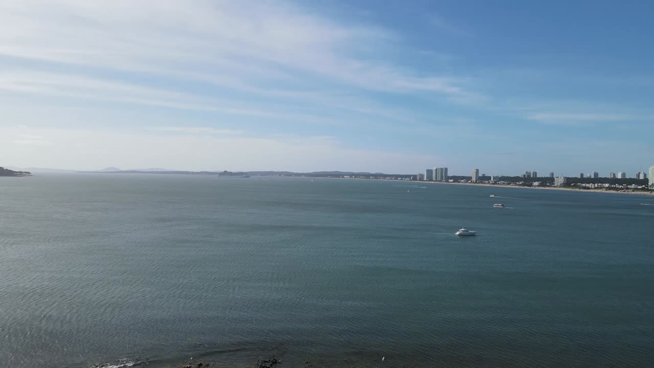 Luxury yacht gliding along coastline, showcasing urban skyline with pristine waters and blue skies during bright summer day near mexican seascape