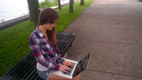 mujer joven escribiendo computadora portátil. chica usando computadora portátil afuera. mujer con computadora portátil afuera