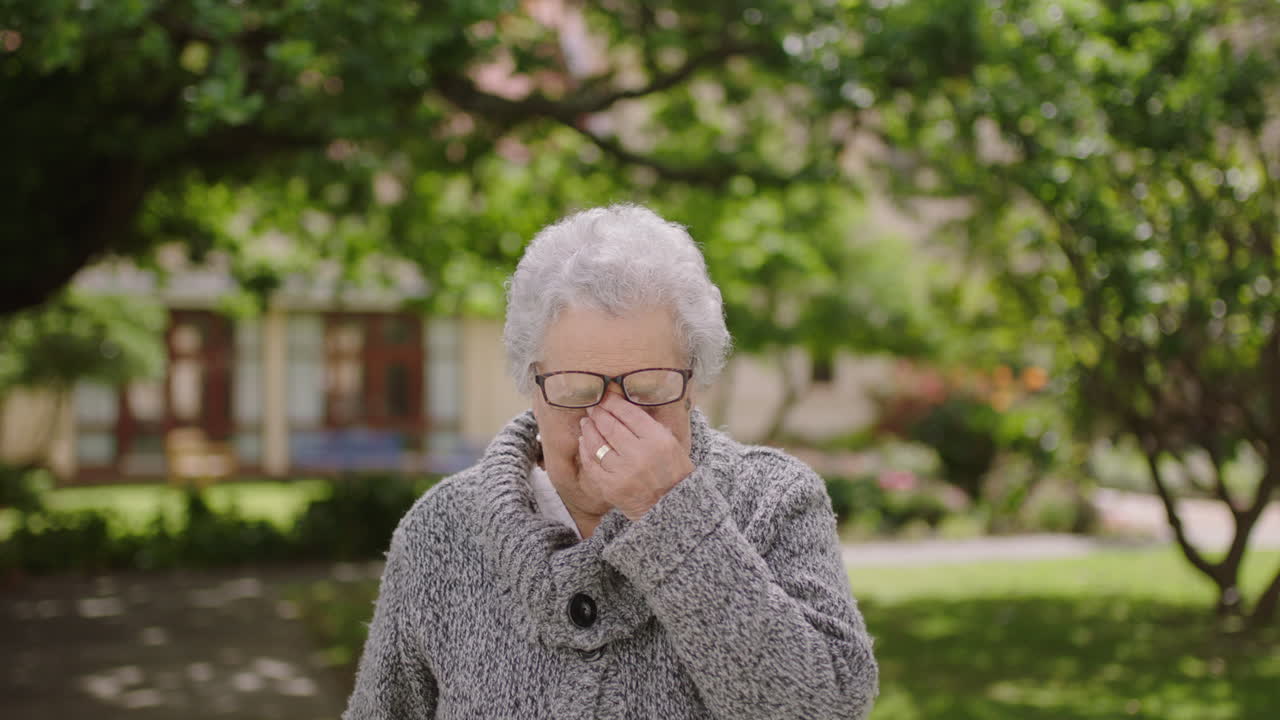 retrato de una anciana jubilada que se siente cansada y somnolienta mirando a la cámara en el fondo del jardín