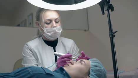 pretty woman listens to patient applying permanent make-up