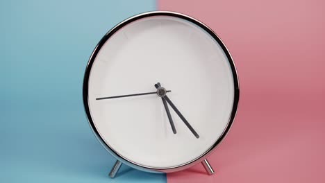 silver clock isolated on blue pink background, time starts walking at 5 o'clock.