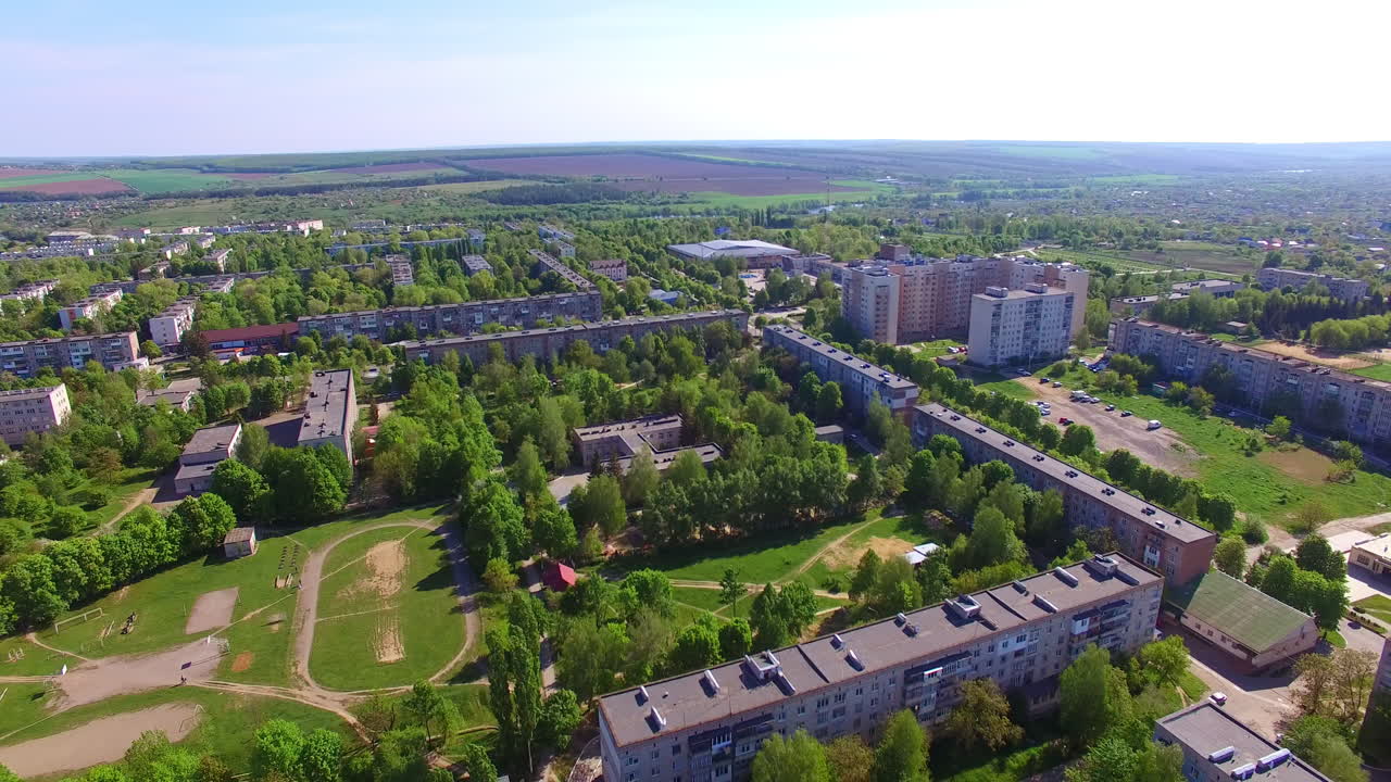 Blocks of flats surrounded by numerous green trees. Beautiful Ukrainian city panorama on sunny summer day.