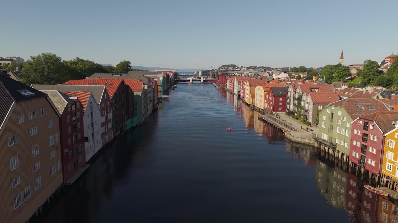 Edifici colorati costeggiano il fiume calmo che attraversa il cuore della città di Trondheim, Norvegia - Drone che vola in avanti
