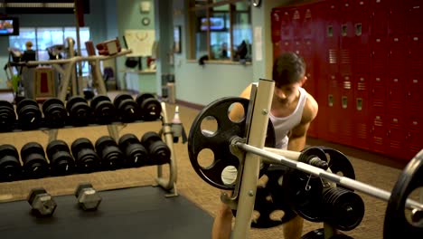 Joven-Culturista-Poniendo-Dos-Pesas-Grandes-En-Una-Barra-En-Un-Gimnasio