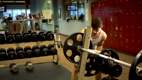teen boy bodybuilder putting a two large weights onto a barbell in a fitness gym