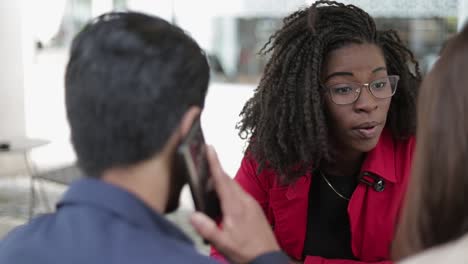 Afro-american-woman-talking-to-couple,-man-talking-on-phone