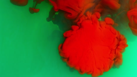 green and red paint or dye dropped into water against white background to create swirling colourful smoke background 1