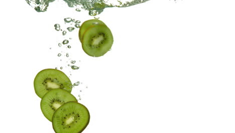 rebanadas de kiwi sumergiéndose en el agua sobre un fondo blanco