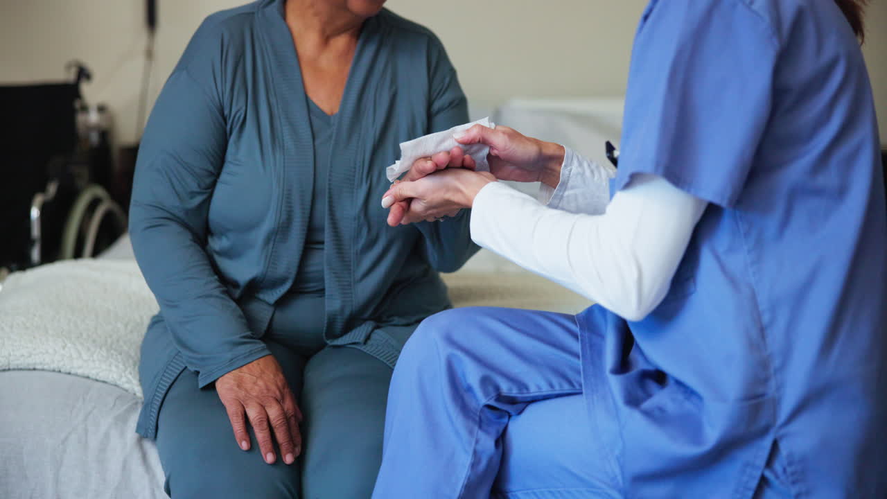 Nurse Holding the Hand of an Elderly Patient in a Hospital Room