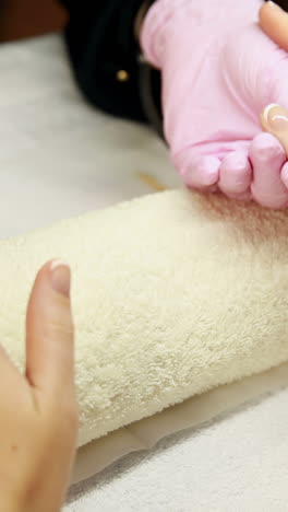técnico de uñas pintando la capa superior en las uñas de los clientes