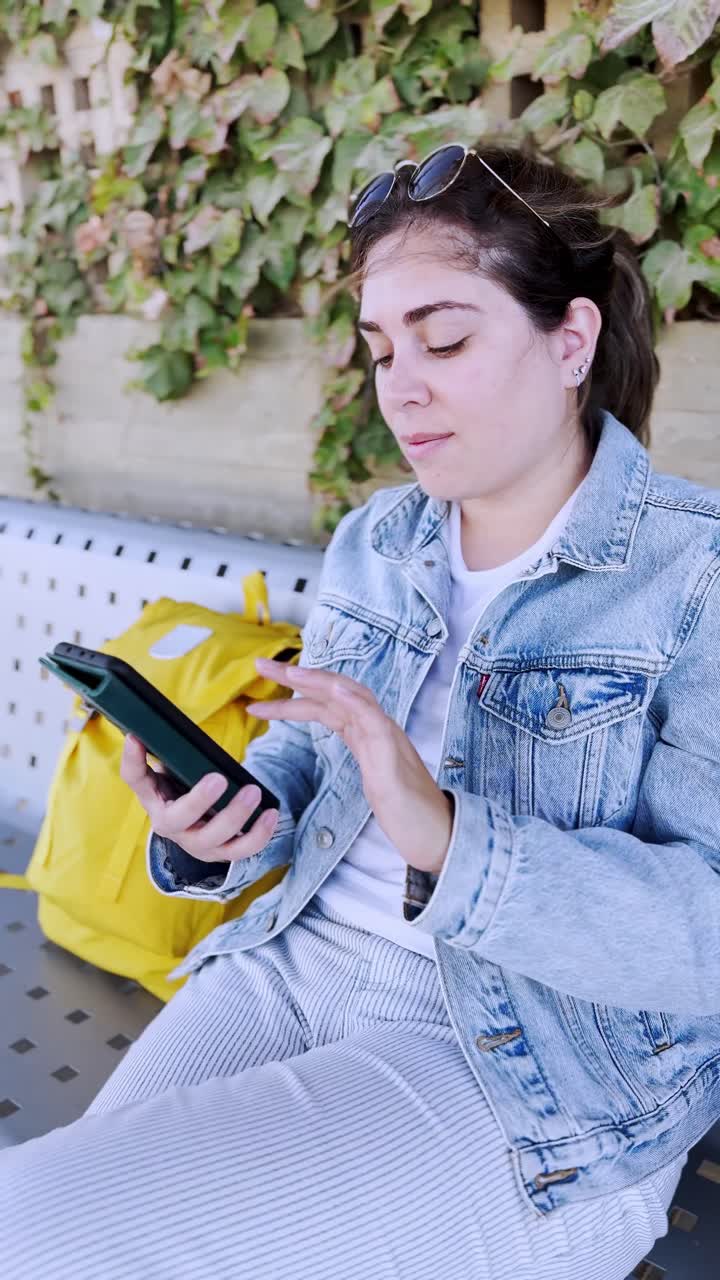 Young Woman Typing on Her Smartphone at a Train Station