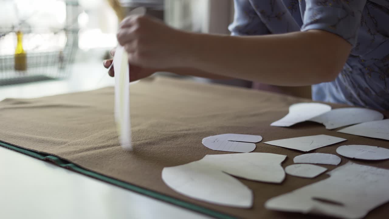 Unrecognizable female designer putting on different patterns on fabric