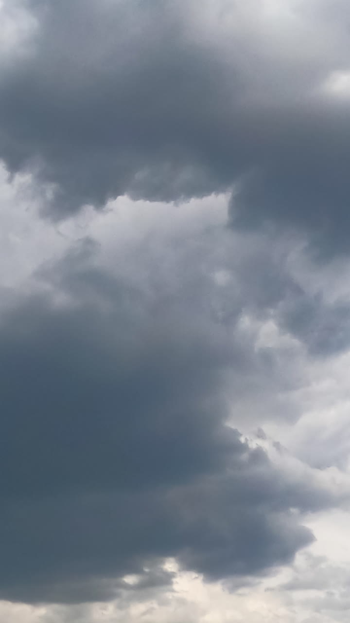 Stormy grey clouds accumulating in the atmosphere. Cumulus cloudscape formation in the sky from low angle view. Timelapse. Vertical video