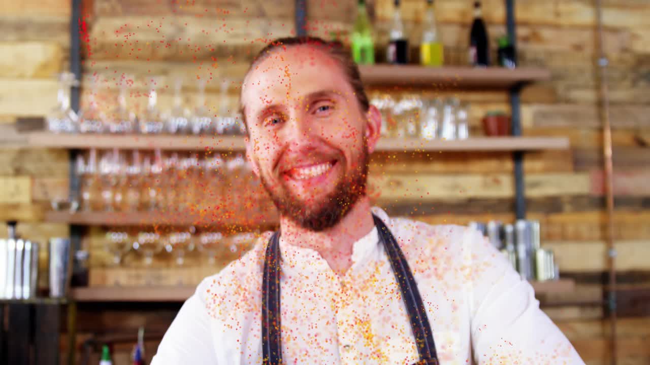 Un barista che sposta una tazza, facendo roteare spezie scintillanti sul bancone, mentre la telecamera si sposta rivelandolo sorridente.
