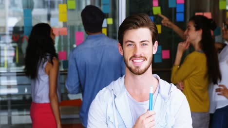 Portrait-of-smiling-male-executive-standing-with-marker