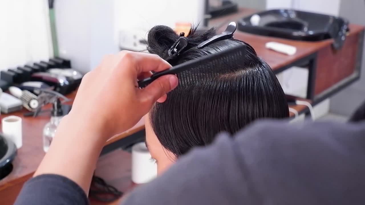 Professionel frisør styler en flot fyr med en elektrisk hårklipper i en barbershop.