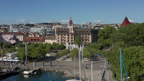 drone flying over yacht harbor towards clock tower in downtown lausanna, switzerland