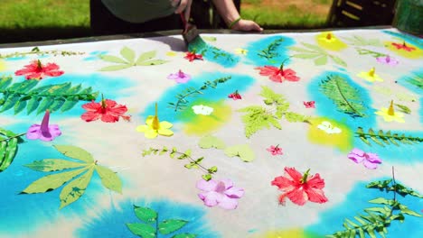 clients learning homemade batik, sarong, pareo, placing blue paint on leaves on white cloth, mahe seychelles 25fps 4