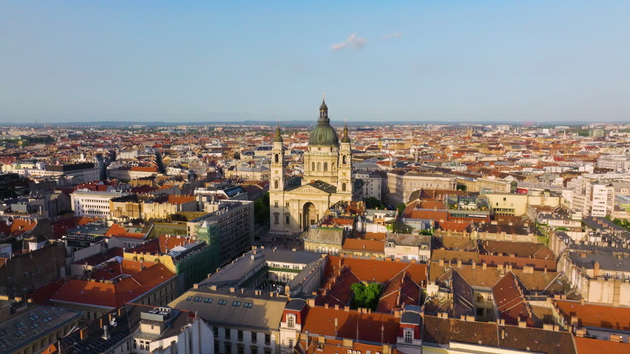 Aerial View Of St. Stephen’s Basilica In Budapest At Sunset Surrounded By Warm-lit Rooftops And Cityscape.