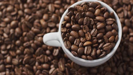 video de una taza de granos de café sobre granos de café marrones tostados