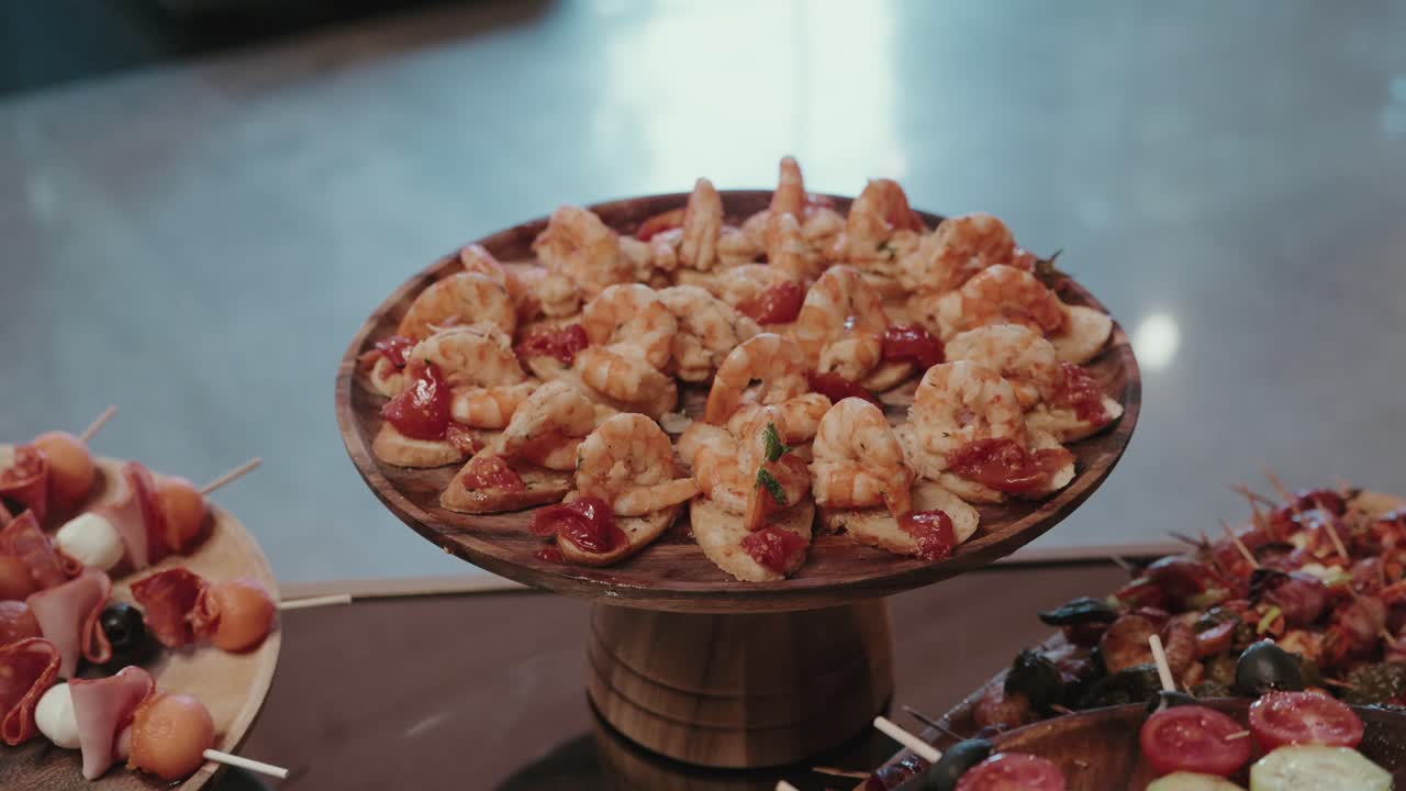 bite sized shrimp appetizers with cherry tomatoes on mini crackers displayed on a wooden tray