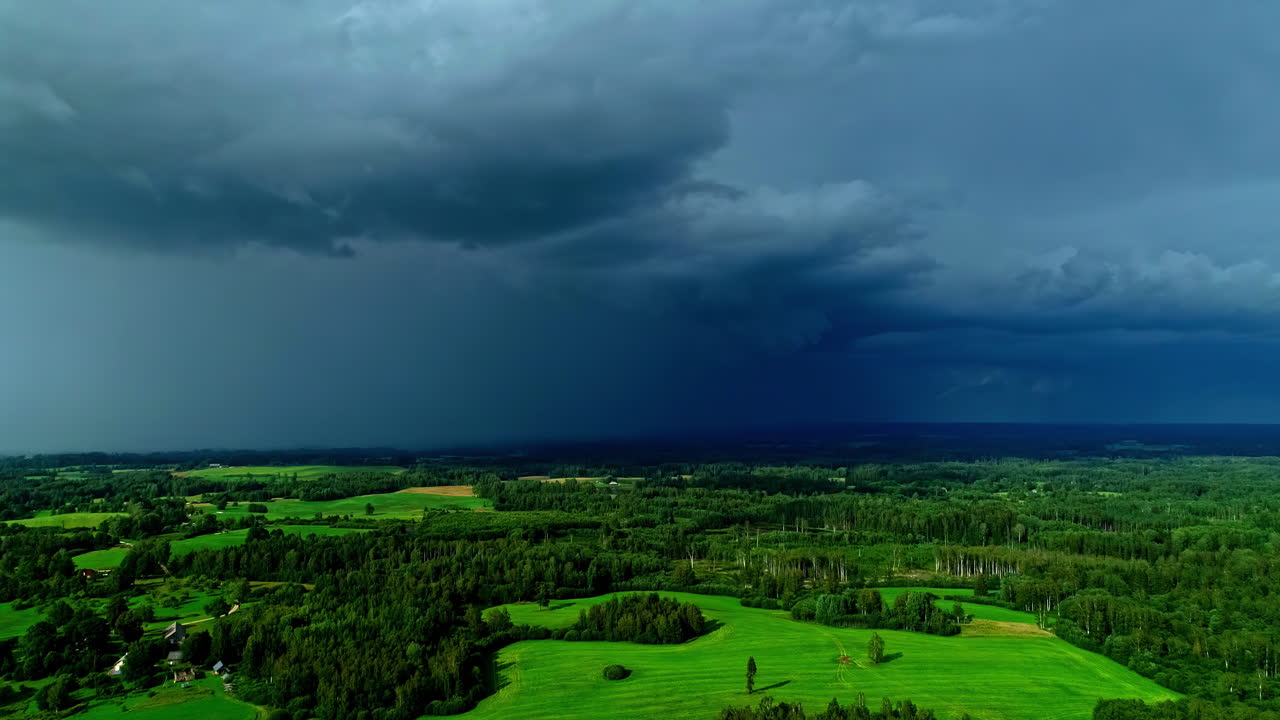 Static shot of thunderstorm in the horizon, epic sky clouds with dark storm front, forests, grass, copy space